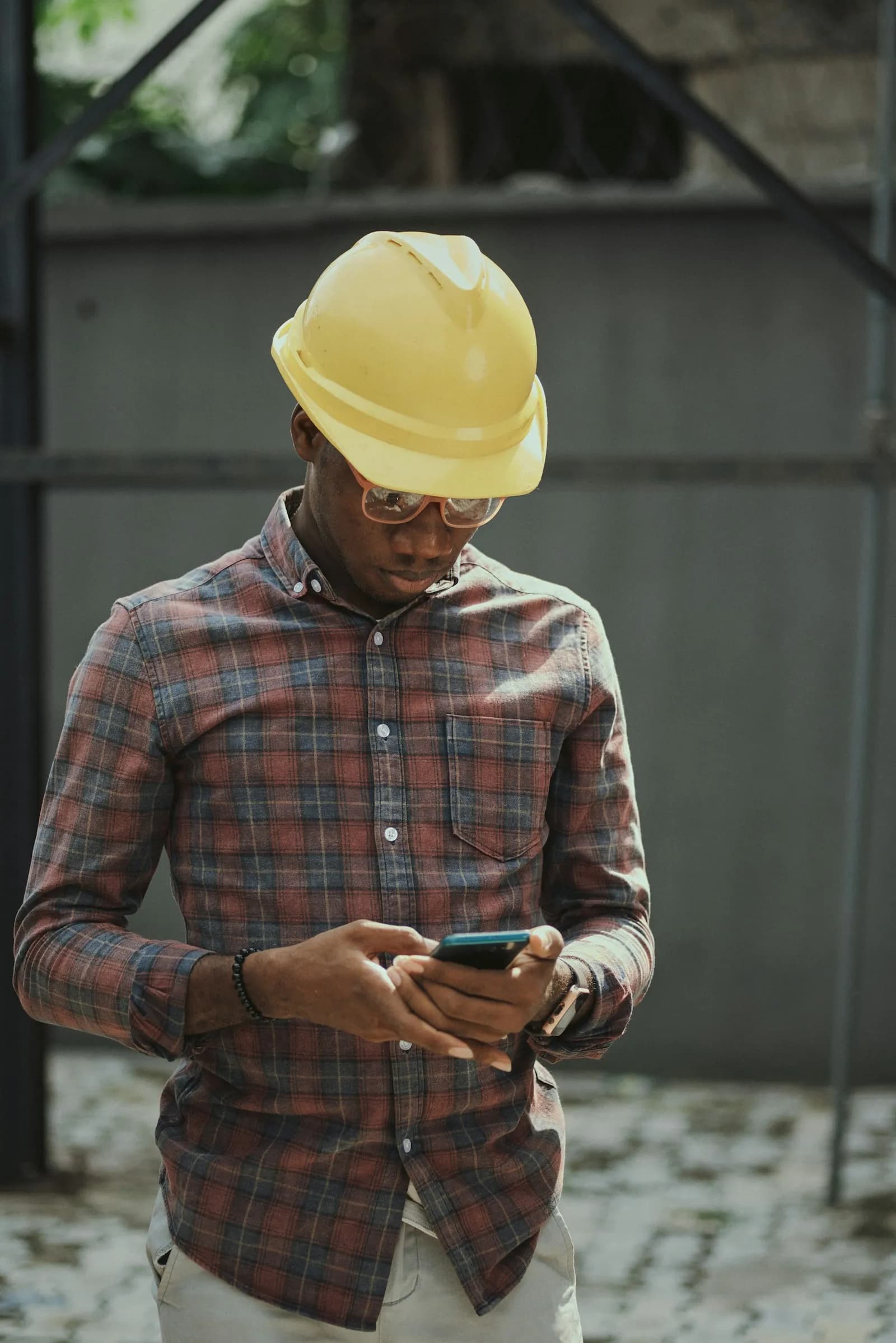 A contractor in a yellow hard hat checking his phone