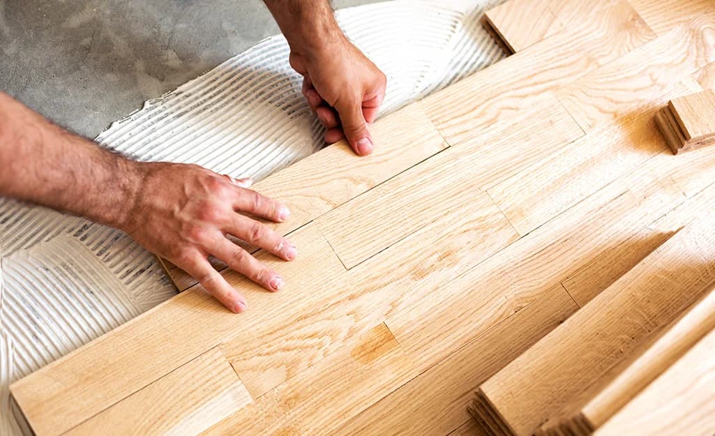 Hands laying new hardwood flooring