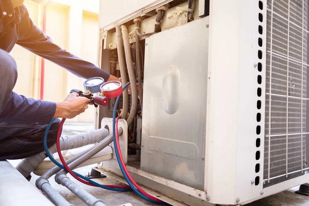 A technician checking an AC unit with pressure gauges