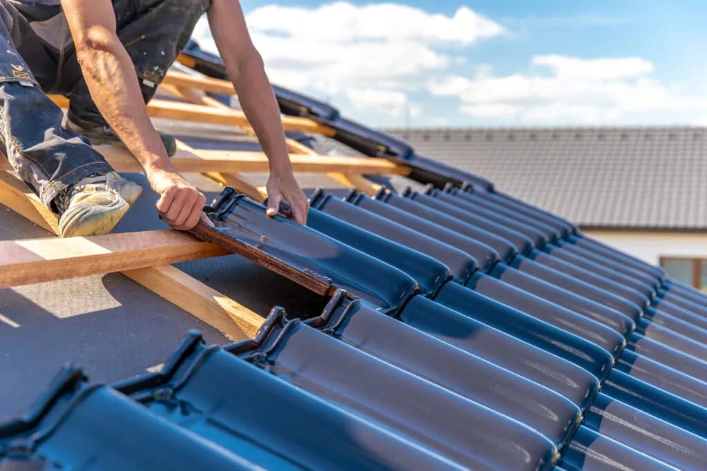 A roofer laying new tiles on a roof