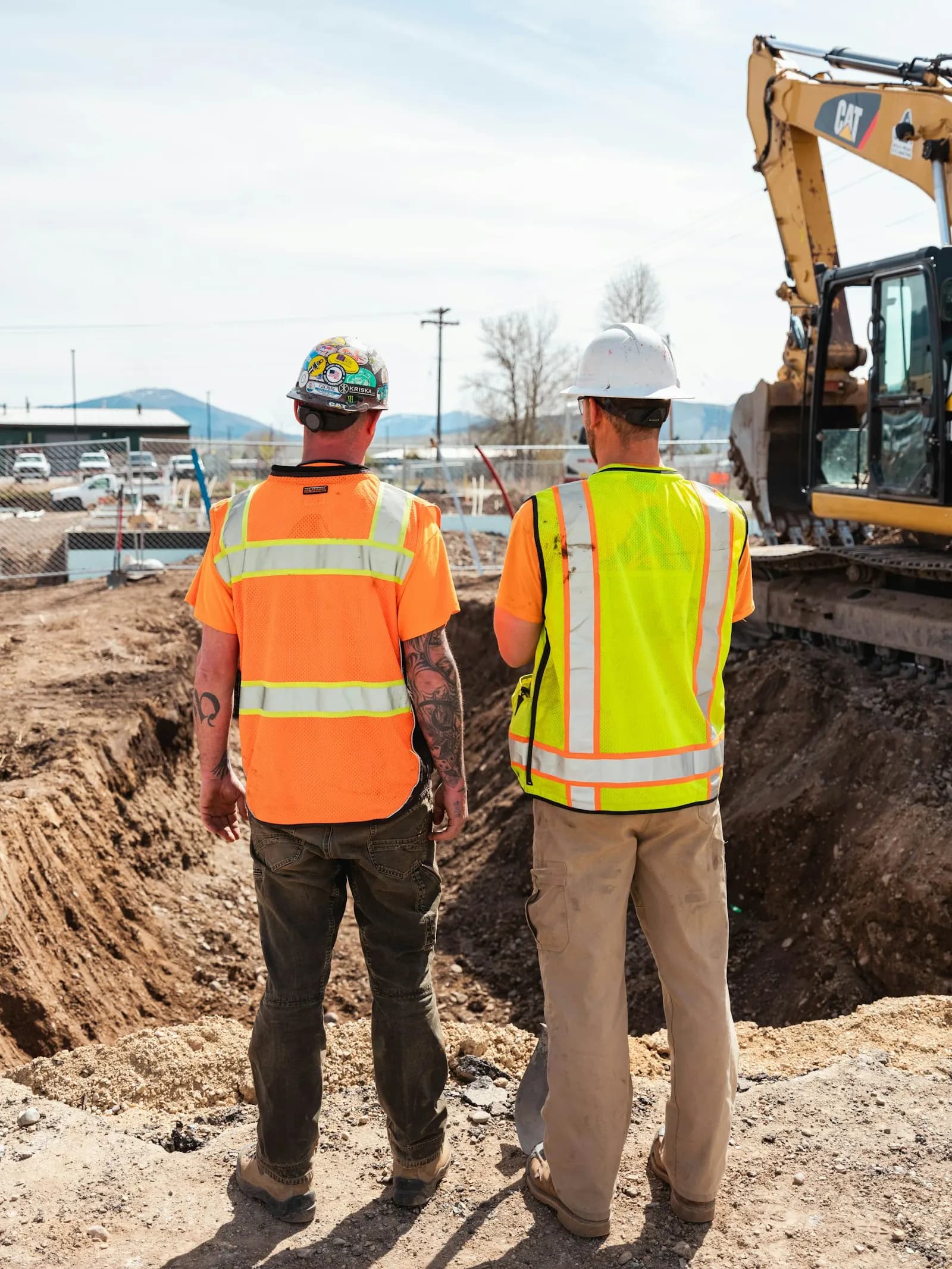 Two construction workers in safety vests on a job site