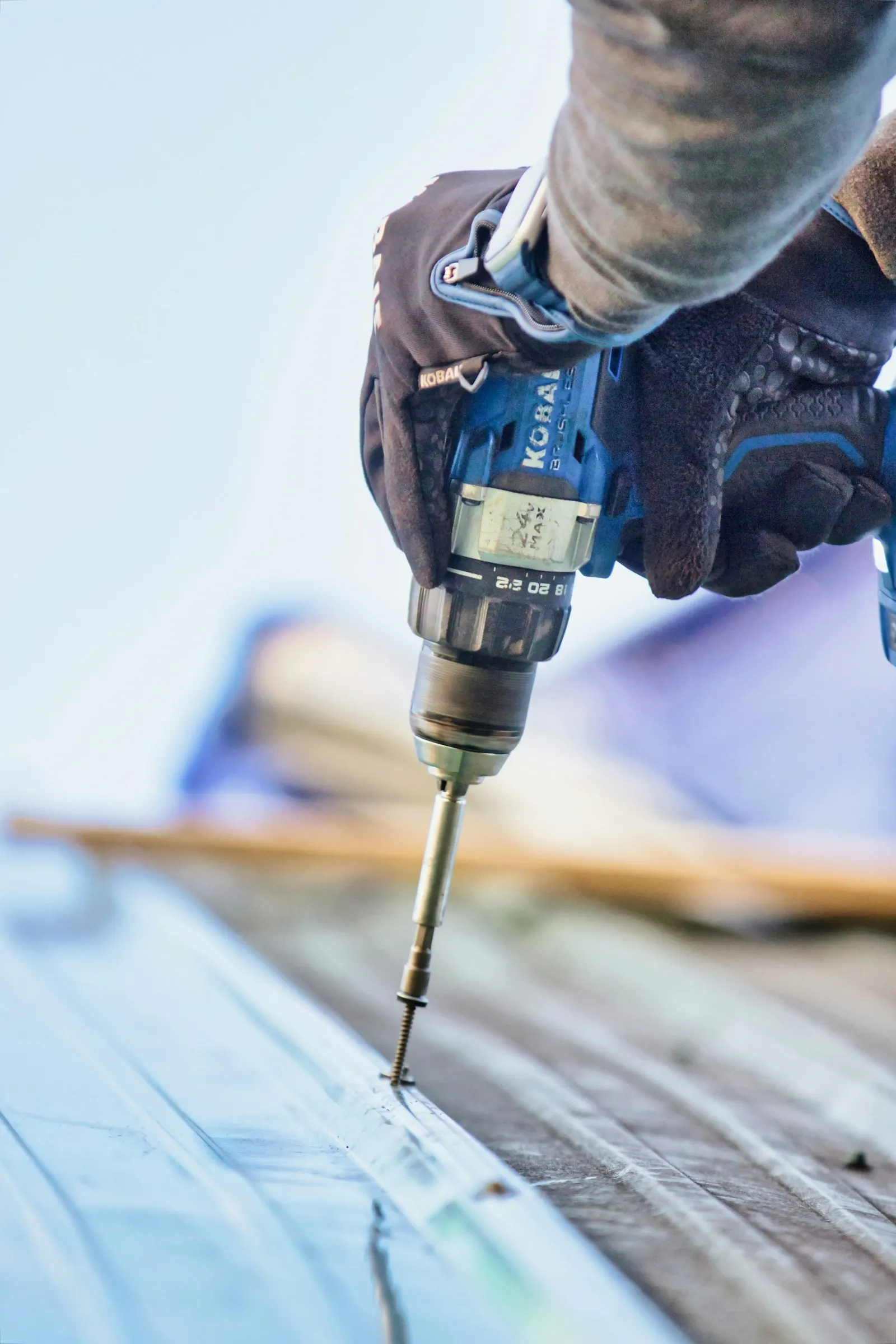 A carpenter driving a screw into a wooden beam